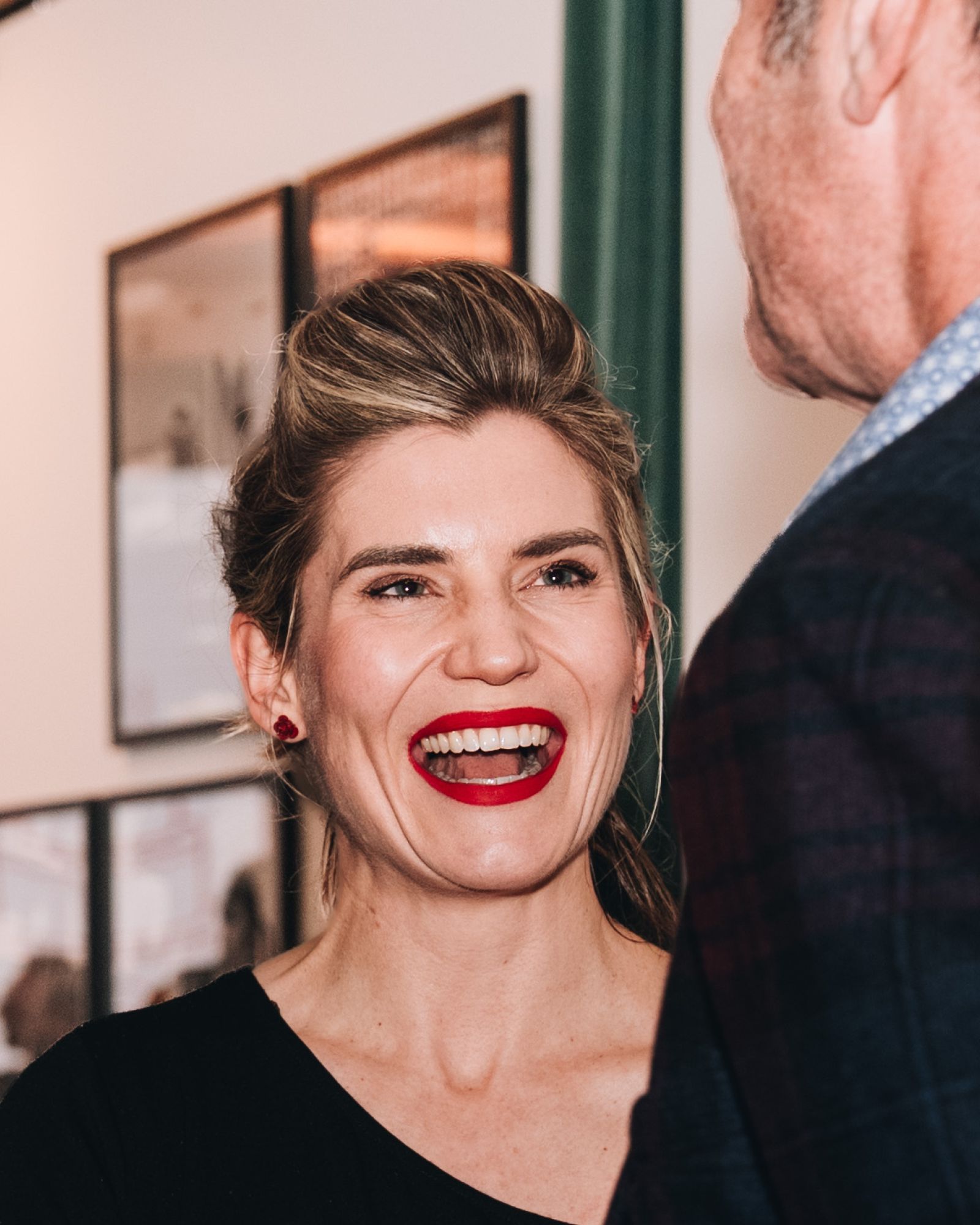 Hanna has blonde hair, red lipstick and is laughing