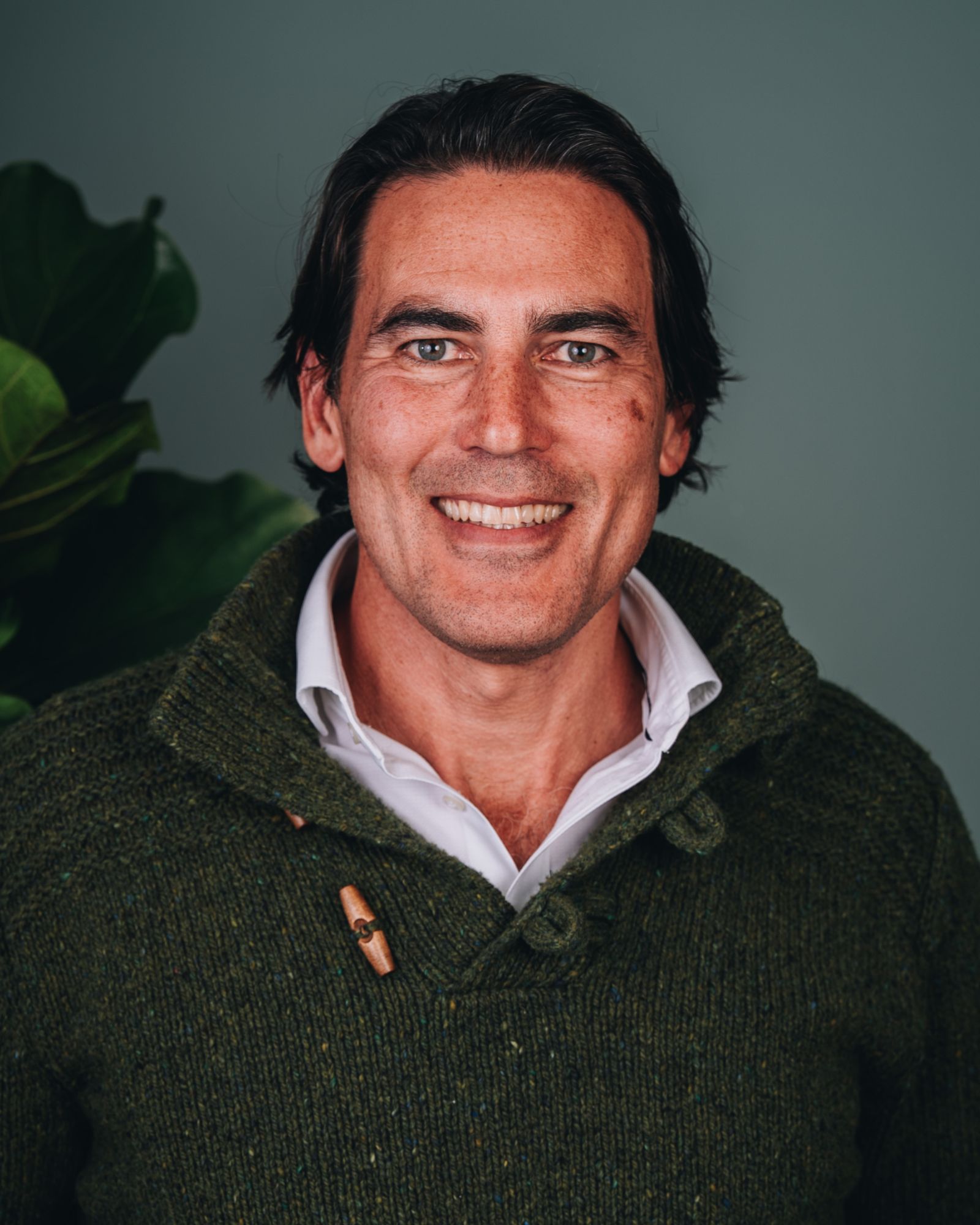 Ben wears a dark green knit jumper, with a great big smile